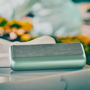 A Jade Green IQOS ILUMA PRIME Pocket Charger on a table.